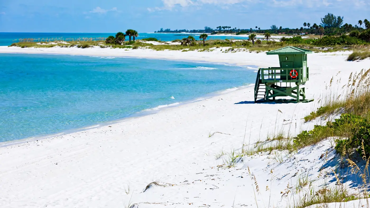 Water damage restoration in Orchid, FL: a white sand Gulf beach with a green lifeguard tower